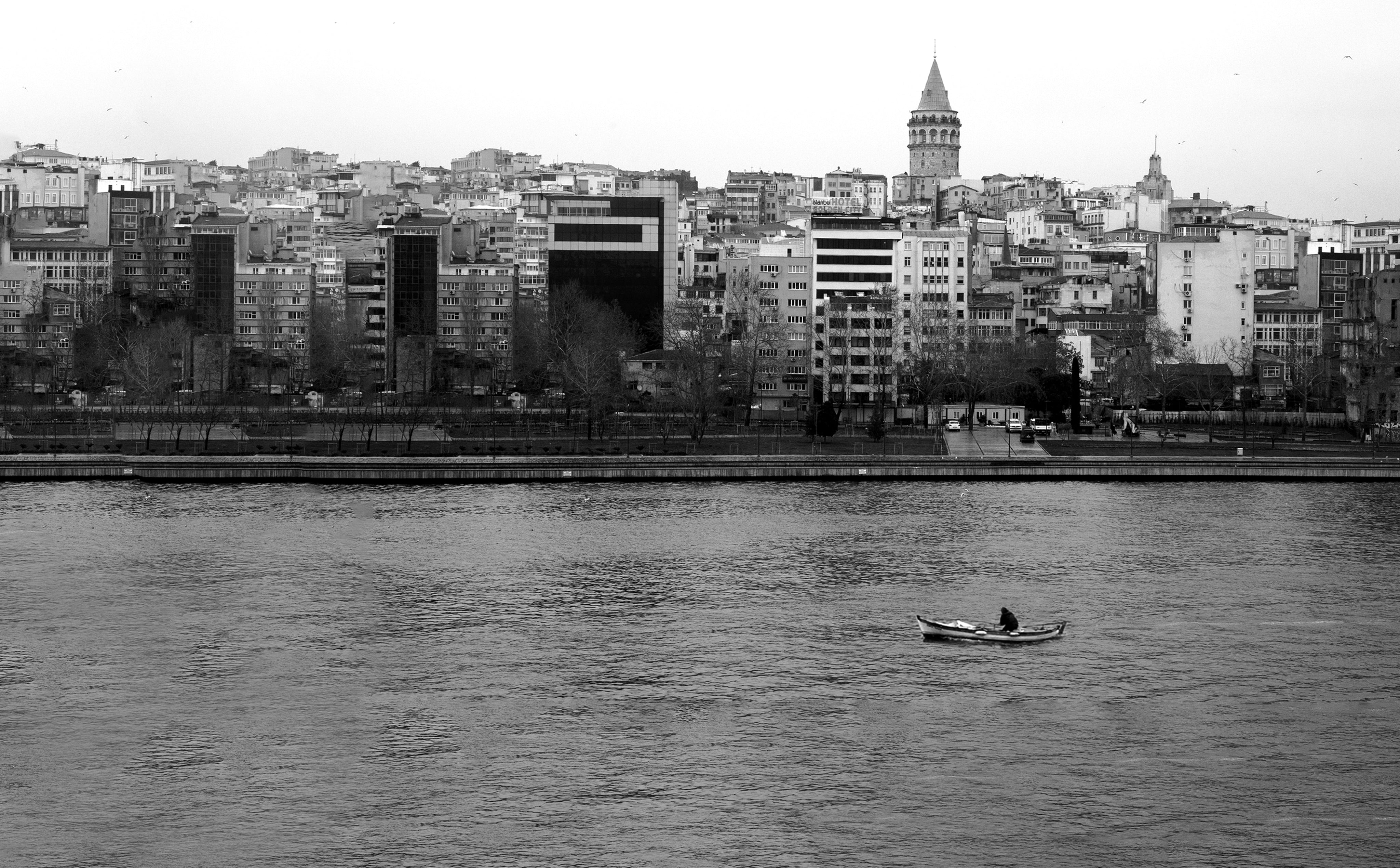 Person on a boat in the water next to a city